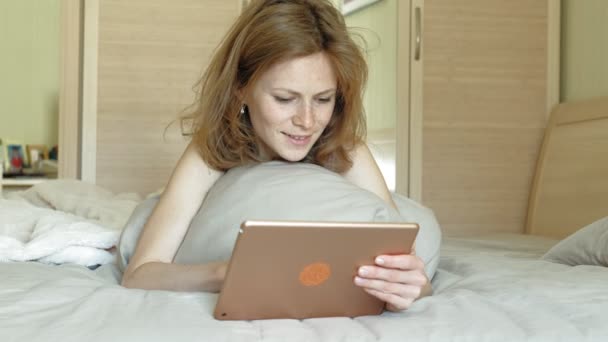 Vrouw in bed met een computer tablet. Goedemorgen. — Stockvideo