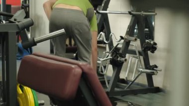 Kilolu bir adam spor salonunda dururken bir ez barbell kaldırır. Pazı için egzersiz. Fitness. Sağlıklı yaşam tarzı.