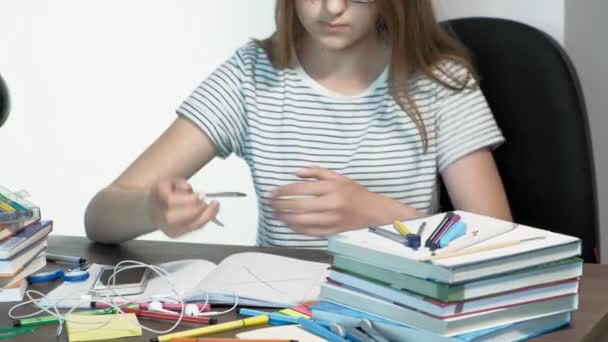 Un'adolescente con gli occhiali e 'seduta alla scrivania di una scuola. concetto di apprendimento — Video Stock