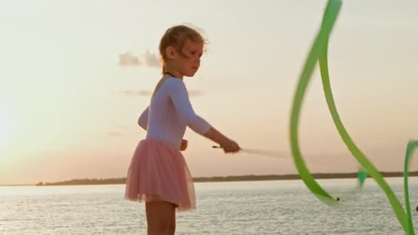 Menina menina pré-escolar com fita de ginástica. Verão, pôr do sol — Vídeo de Stock