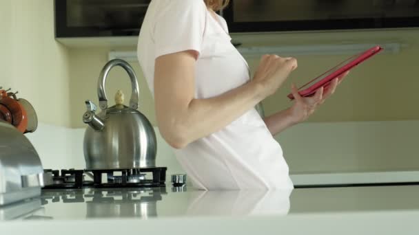 A nő a konyhában használja a tablettát, csak felébredt. Reggeli. Kora reggel — Stock videók