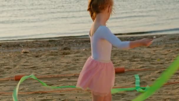 Дівчинка дошкільного віку з гімнастичною стрічкою. Літо, захід сонця — стокове відео