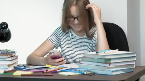 Una adolescente con gafas está sentada en un escritorio de la escuela. concepto de aprendizaje — Vídeos de Stock