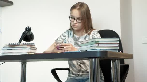 Gözlüklü bir genç kız bir okul masasında oturuyor. öğrenme konsepti — Stok video