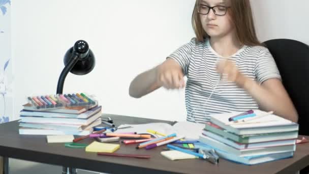 Een tiener meisje met een bril zit aan een school Bureau. Leer concept — Stockvideo