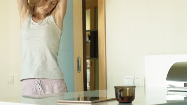 La mujer de la cocina usa la tableta, acaba de despertarse. El desayuno. Temprano. — Vídeo de stock