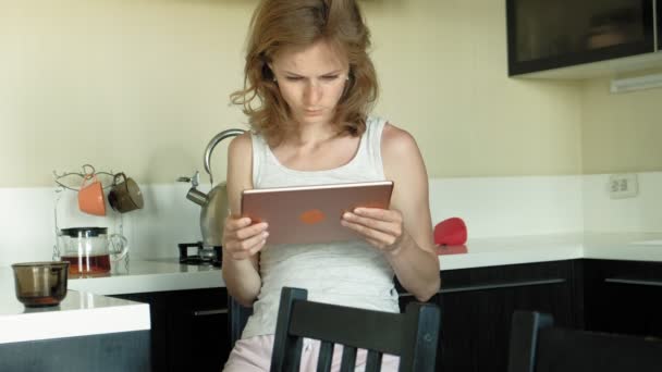 De vrouw in de keuken maakt gebruik van de Tablet, net wakker. Ontbijt. Vroege ochtend — Stockvideo