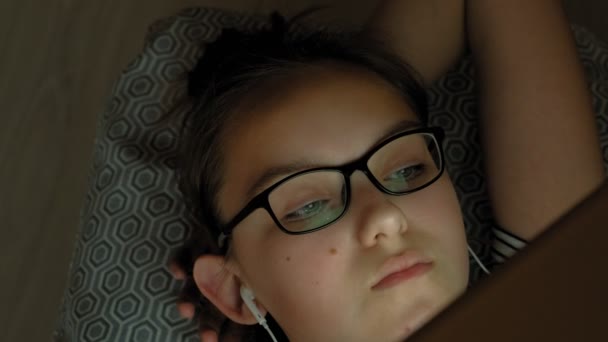 Teen girl utilise une tablette avec écouteurs. Heure du soir — Video
