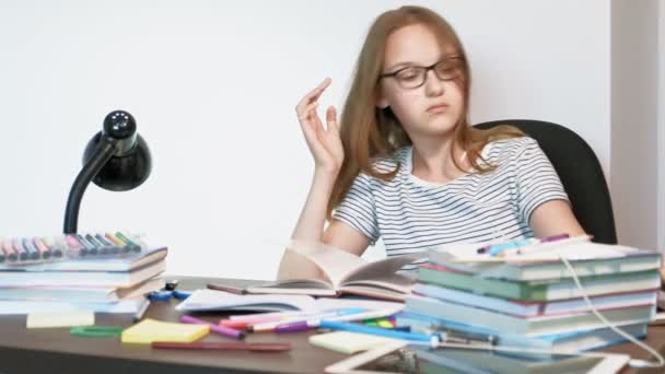 Una adolescente con gafas está sentada en un escritorio de la escuela. concepto de aprendizaje — Vídeo de stock