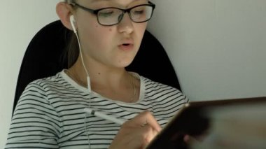 Genç kız kulaklıklı tablet kullanıyor. Akşam saati