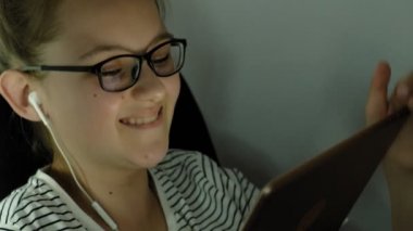 Genç kız kulaklıklı tablet kullanıyor. Akşam saati