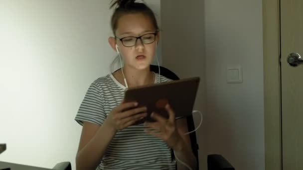 十代の女の子は、ヘッドフォンとタブレットを使用しています。夕方の時間 — ストック動画