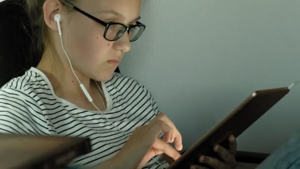 Teen girl utilizza tablet con cuffie. Ora di sera — Video Stock