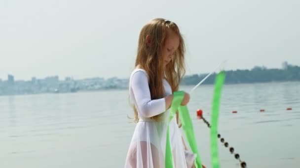 Vorschulmädchen tanzt ein Gymnastikband an einem Sandstrand. Sommer, Morgengrauen — Stockvideo