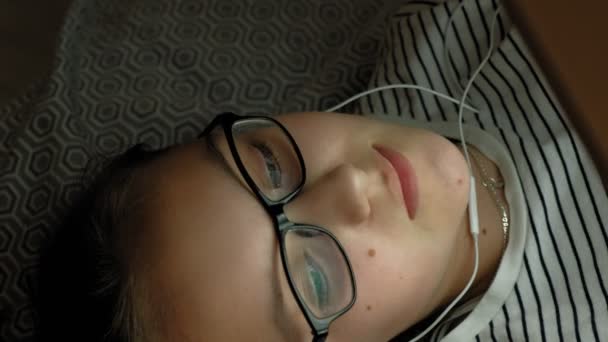 Adolescente usa tablet com fones de ouvido. Hora da noite — Vídeo de Stock