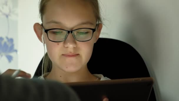 십대 소녀는 헤드폰태블릿을 사용합니다. 저녁 시간 — 비디오