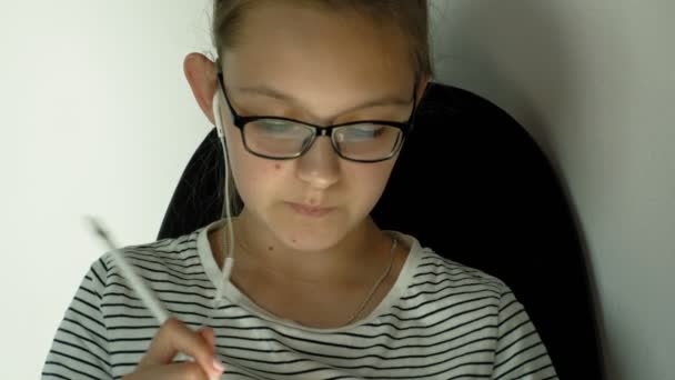 Chica adolescente utiliza la tableta con auriculares. Hora de la tarde. — Vídeos de Stock