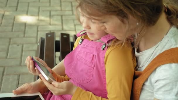 Mãe e filha usam aparelhos ao ar livre. Verão — Vídeo de Stock