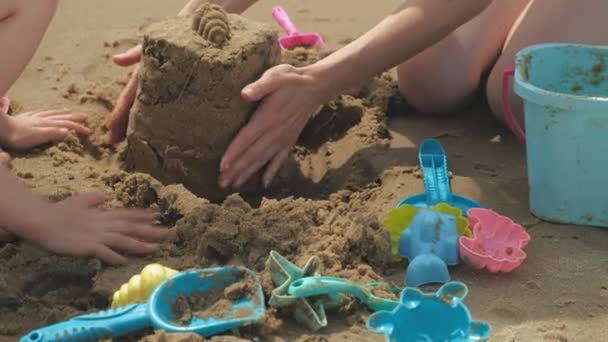 Mãe e filha estão brincando na praia, construindo um castelo de areia. Dia ensolarado de verão. férias — Vídeo de Stock