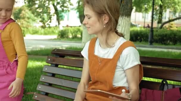 Mamá y su hija usan aparatos al aire libre. Verano — Vídeos de Stock