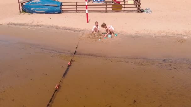 妈妈和女儿在沙滩上玩，建造一座沙堡。夏天阳光明媚。假期。空中拍摄 — 图库视频影像