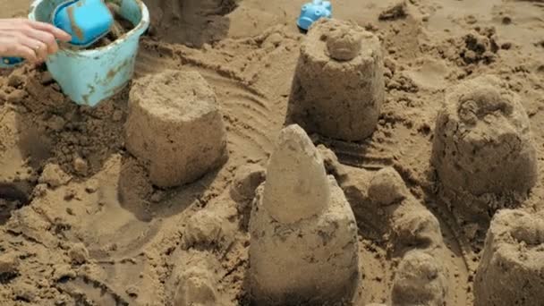 Mãe e filha estão brincando na praia, construindo um castelo de areia. Dia ensolarado de verão. De férias. Tiro aéreo — Vídeo de Stock