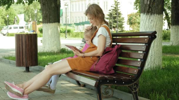 Mom and daughter use gadgets in the open air. Summer — Stock Video