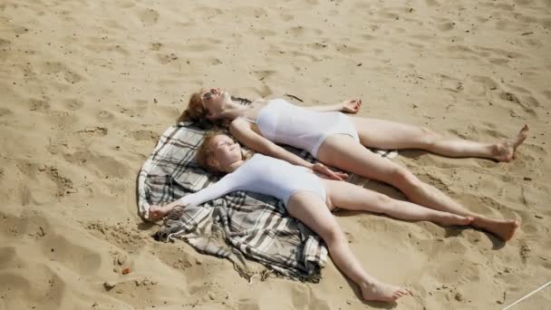 Η μαμά και η κόρη κάνουν ηλιοθεραπεία στην παραλία. Καλοκαιρινή ηλιόλουστη μέρα — Αρχείο Βίντεο