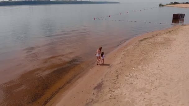 Мать и дочь бегут вдоль реки по песку. Пляж Солнечный летний день. Аэросъемка — стоковое видео