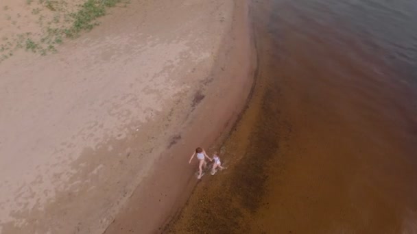 Matka s dcerou utíšeli podél řeky podél písku. Pláže. Slunný letní den. Letecká výstřela — Stock video