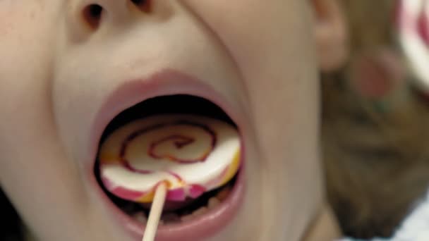 Little girl with a lollipop lies on a blue background. Closeup portrait, top view — Stock Video