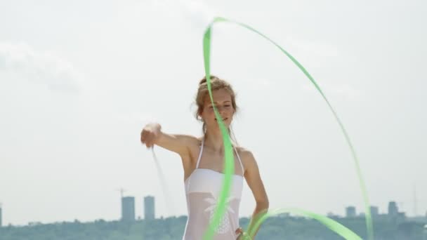 体操のリボンで踊る砂浜の上に白い体の若い女性体操選手。夏、夜明け — ストック動画