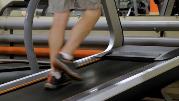 Hombre joven fuerte en la cinta de correr en el gimnasio — Vídeo de stock