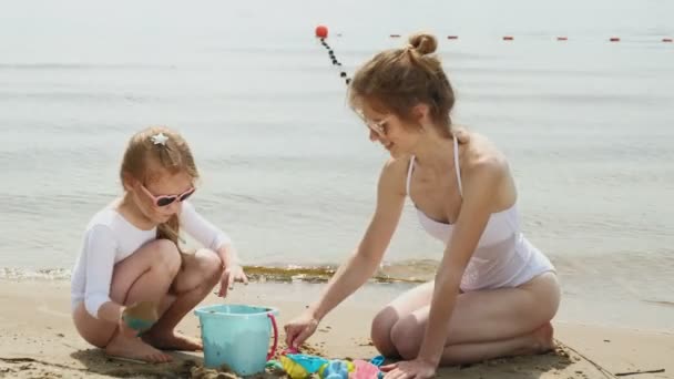 Мама и дочь играют на пляже, строят замок из песка. Летний солнечный день. отпуск — стоковое видео