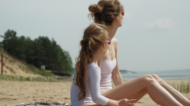 Mutter und Tochter sonnen sich am Strand. Sommer sonniger Tag — Stockvideo