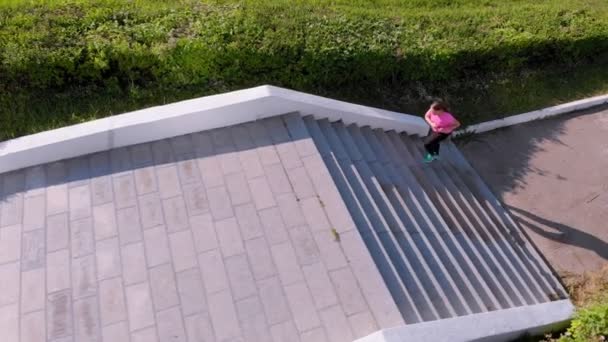 Ein junges Mädchen rennt die Treppe hinauf, beim Sport. Luftaufnahmen — Stockvideo