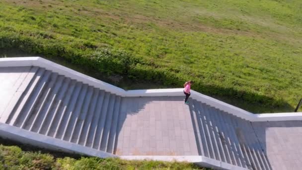 Una joven sube por las escaleras, hace deporte. Disparo aéreo — Vídeos de Stock