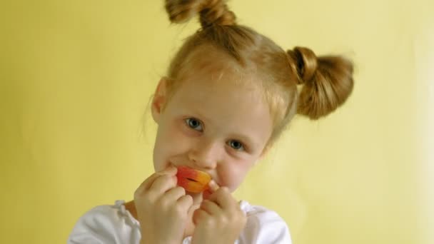 Cheerful little girl on a yellow background with color jelly. Closeup portrait. — Stock Video