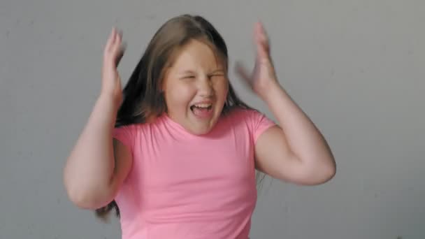 Chica adolescente en un fondo gris representa emociones — Vídeos de Stock