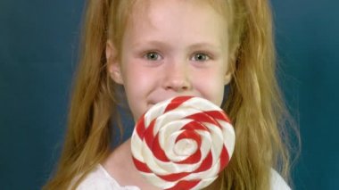 Mavi arka planda lolipopu olan küçük bir kız. Portreyi kapat