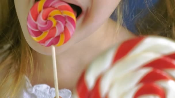 Little girl with a lollipop on a blue background. Close up portrait — Stock Video