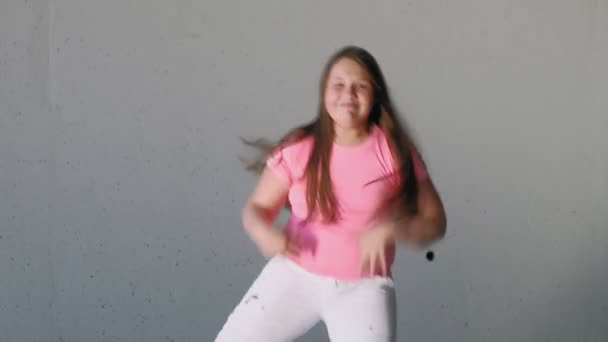 Lány tinédzser táncol egy szürke háttér. Utcai tánc — Stock videók