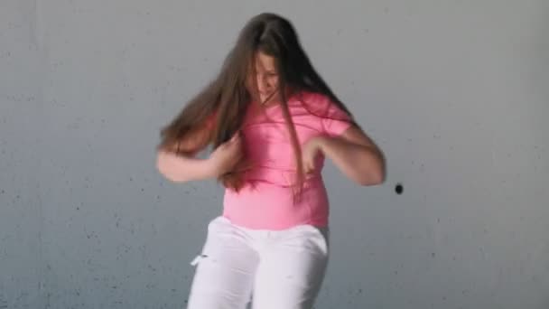 Chica adolescente bailando sobre un fondo gris. Baile callejero — Vídeos de Stock