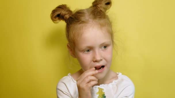 Vrolijk klein meisje op een gele achtergrond met Color Jelly. Close-up portret. — Stockvideo