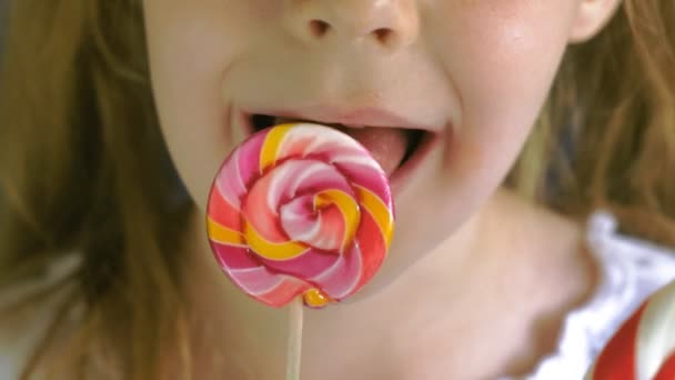 Little girl with a lollipop on a blue background. Close up portrait — Stock Video