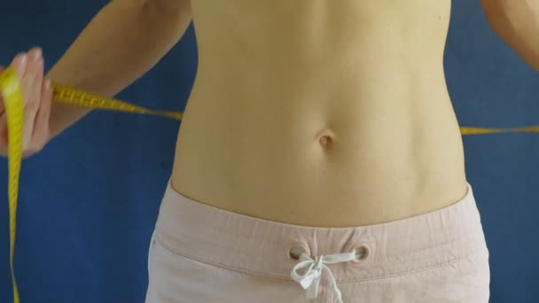Mujer con el vientre plano. Primer plano sobre un fondo azul. Comida saludable, fitness — Vídeos de Stock