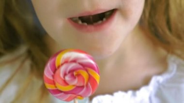 Mavi arka planda lolipopu olan küçük bir kız. Portreyi kapat