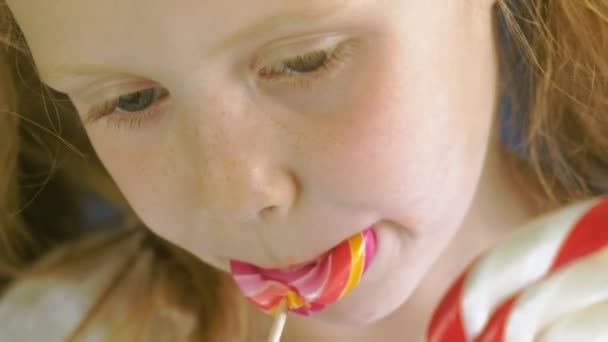 Little girl with a lollipop on a blue background. Close up portrait — Stock Video