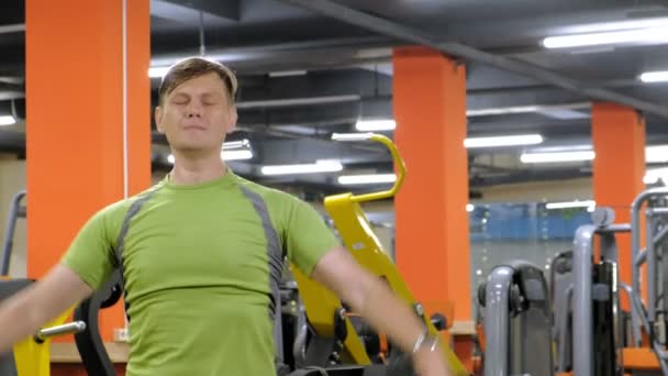 Een man doet een oefening op de rug Delta met dumbbells zittend met een rechte greep in een fitness studio — Stockvideo