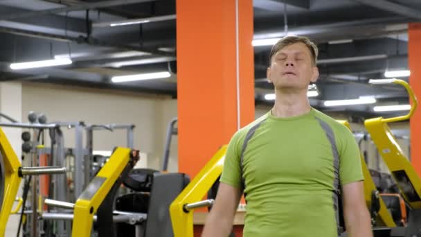 Een man doet een oefening op de rug Delta met dumbbells zittend met een rechte greep in een fitness studio — Stockvideo